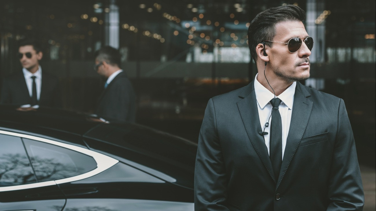 Bodyguard standing at businessman car and reviewing territory