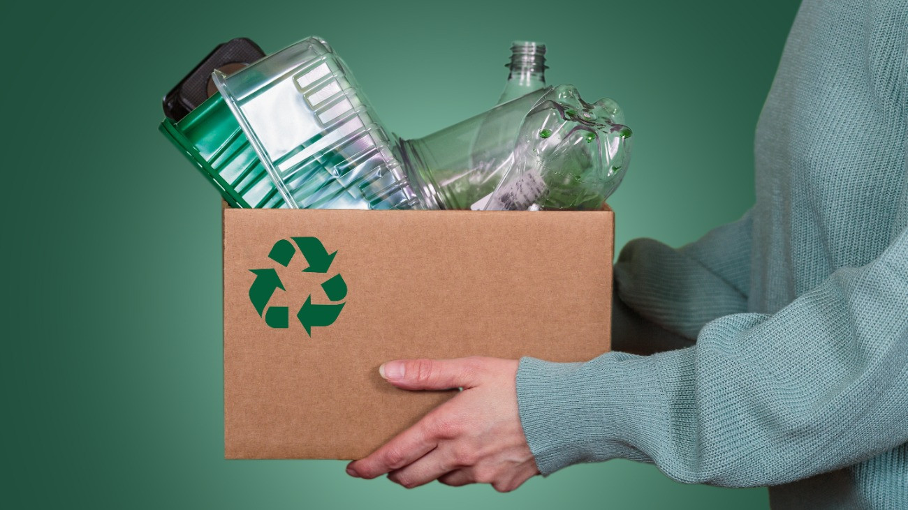 Műanyag hulladékkal teli kartondobozt tart egy nő, hirdetve a környezettudatosságot és a felelős hulladékkezelési gyakorlatot.Forrás: Getty Images/Svittlana Kuchina