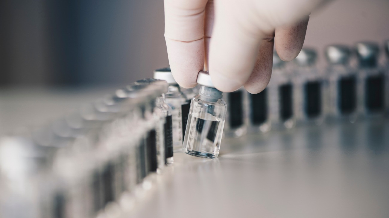 Vakcinát tartalmazó üvegfiolák sokaságából kiemel egyet egy gumikesztyűs egészségügyi dolgozó.Forrás: Getty Images/Emilija Manevska