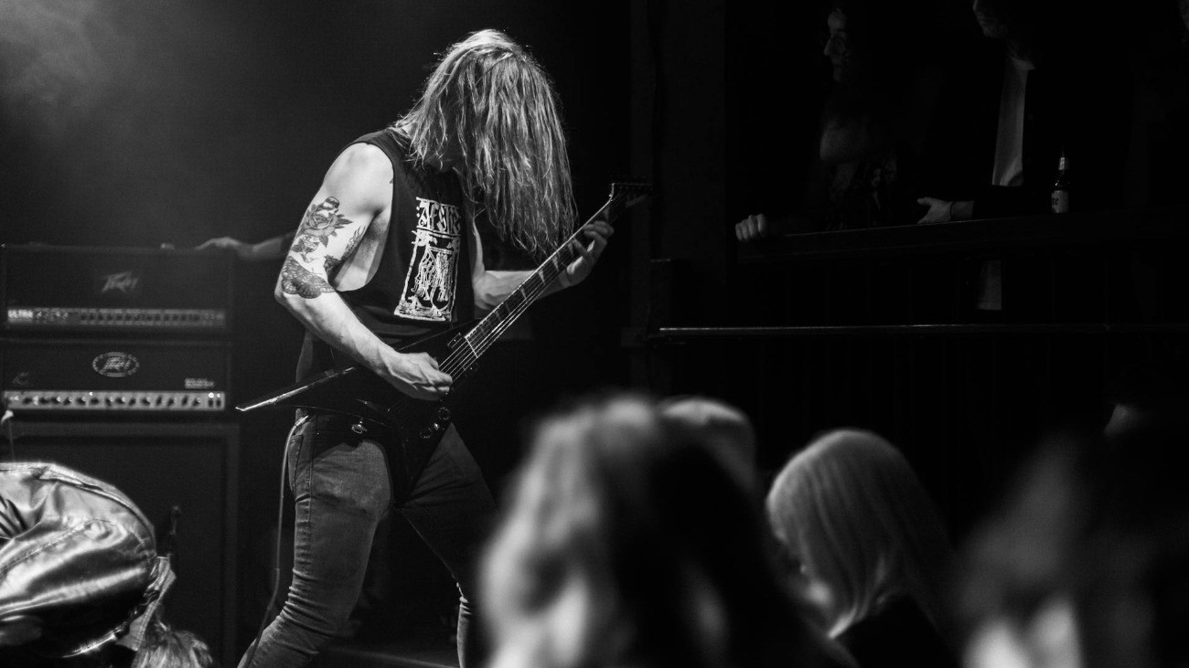 Egy gitáros játszik a színpadon, közönség előtt.