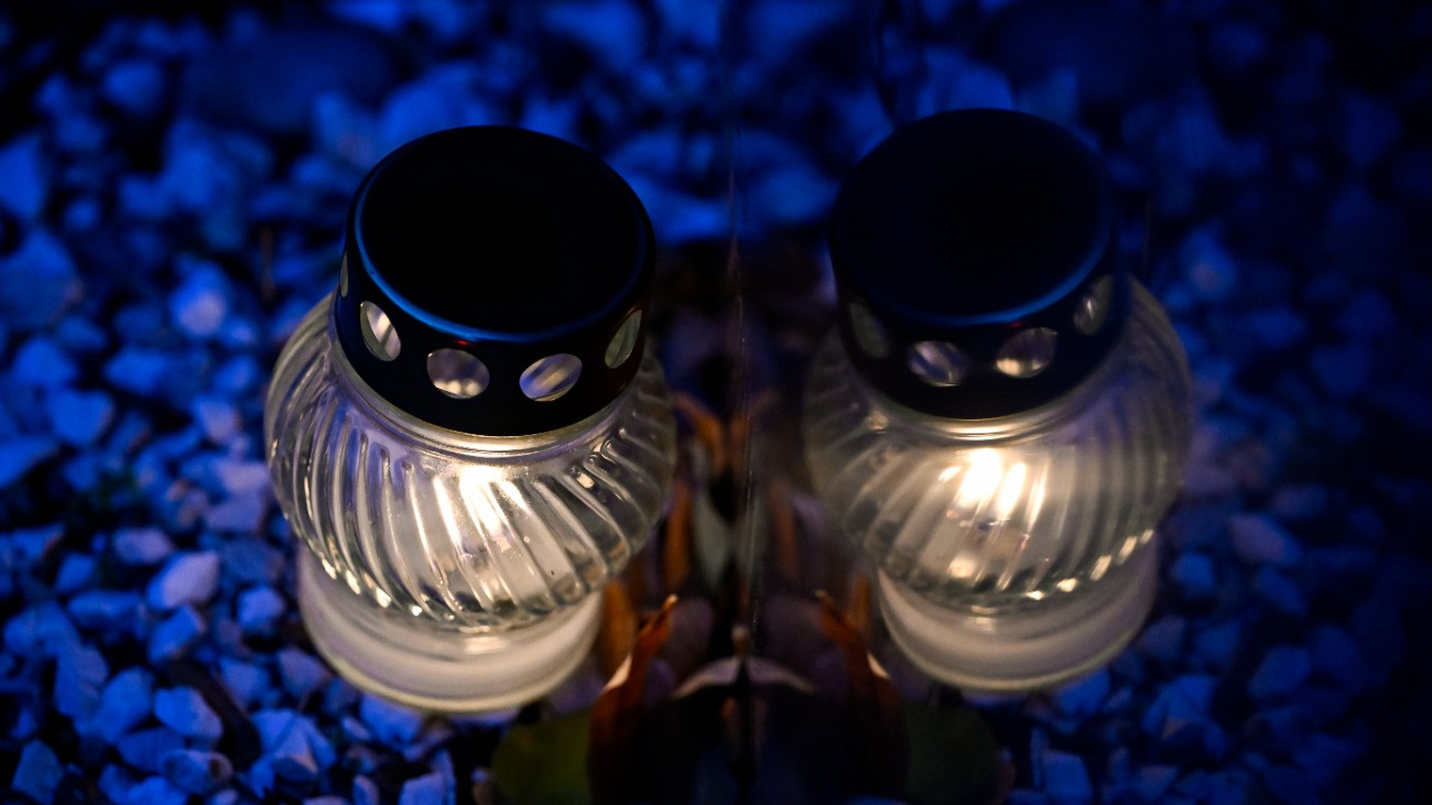 Mécses és tükörképe egy márványtáblán a Fiumei úti sírkertben mindenszentek ünnepe és halottak napja elõtt, 2025. október 30-án.