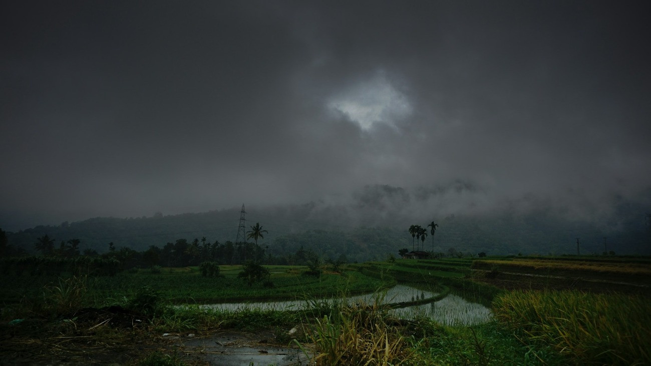 Sötét viharfelhők egy délkelet-ázsiai táj felett.