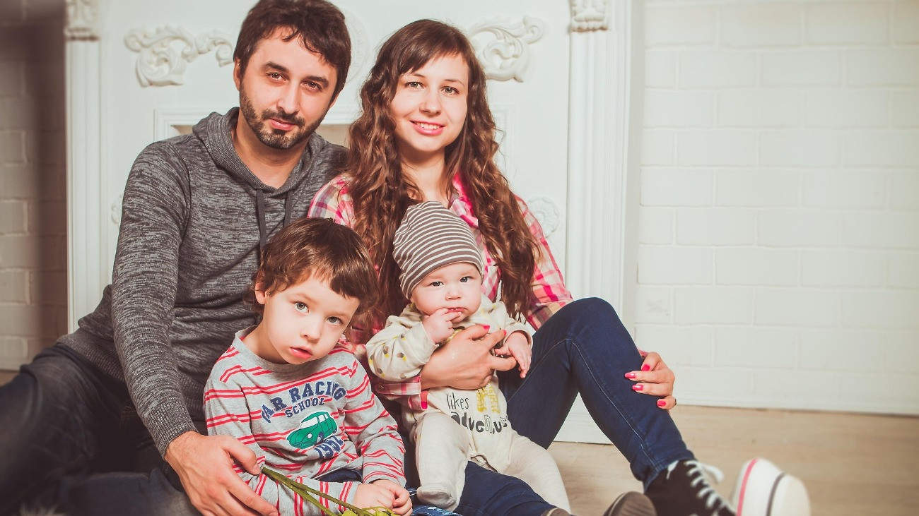 Családi kép, amelyen egy anya, egy apa látható, valamint két kisgyermekük.