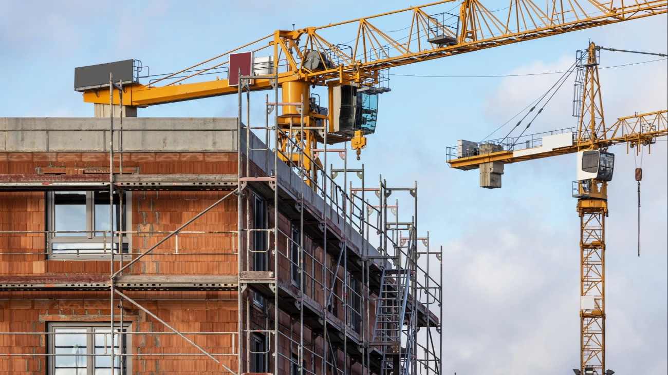 Construction site of a residential building with scaffolding and large cranes