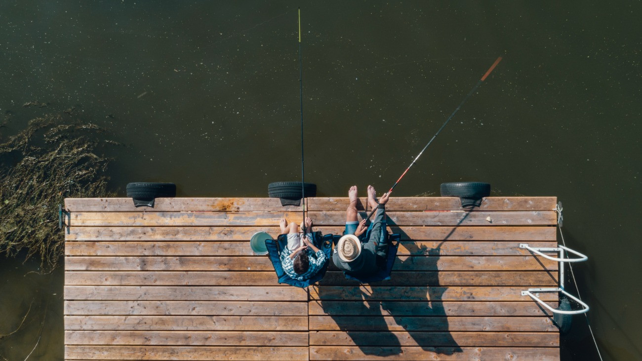 Apa és fia horgászik egy tóparti mólón.