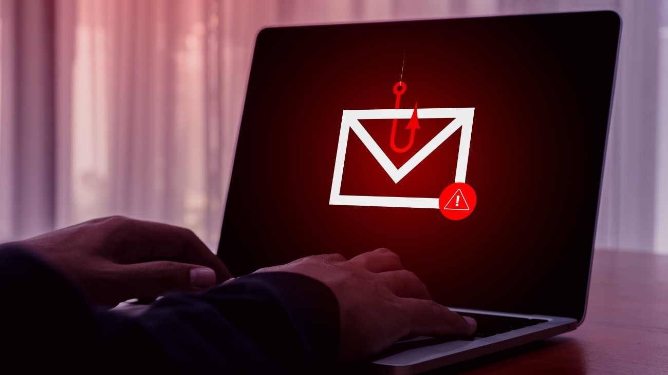 E-mail spam phishing scammer concept. Red warning symbol on envelope in fishing hook icon as bait on laptop screen, criminal hacker cyberattack sending scam malware spreading virus sms text message.