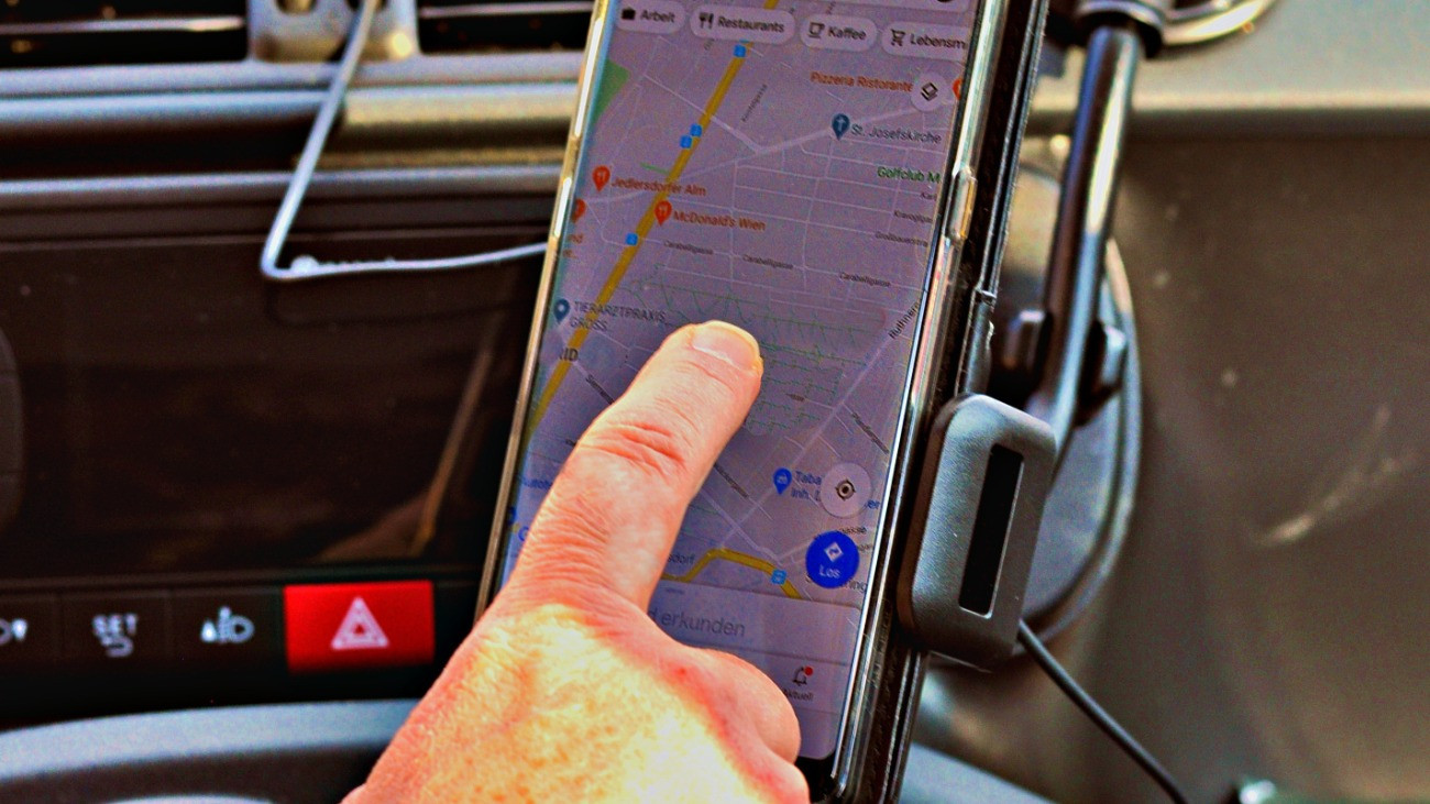 Navigációt kezel okostelefonon egy autóvezető.