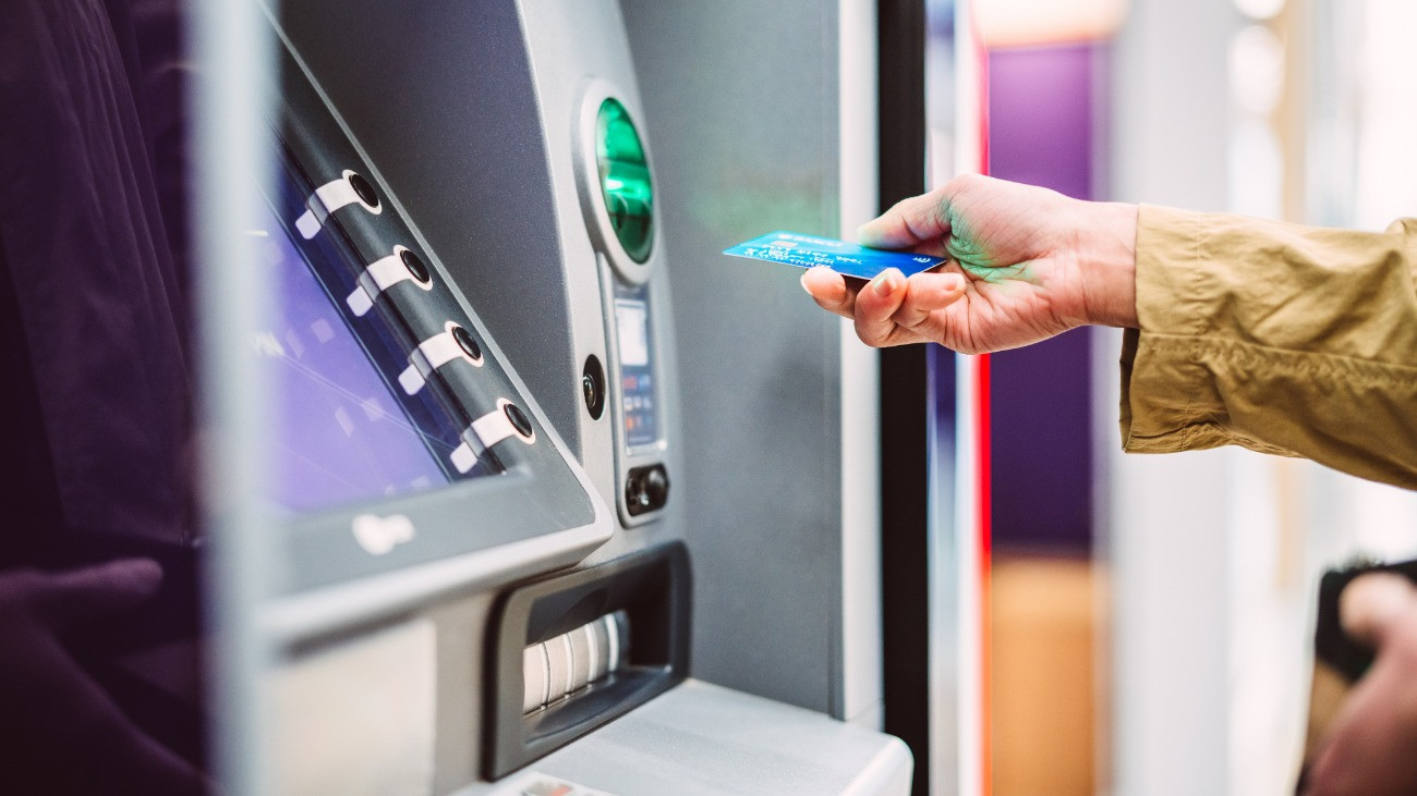 Egy női kéz bankkártyát helyez egy ATM-be.