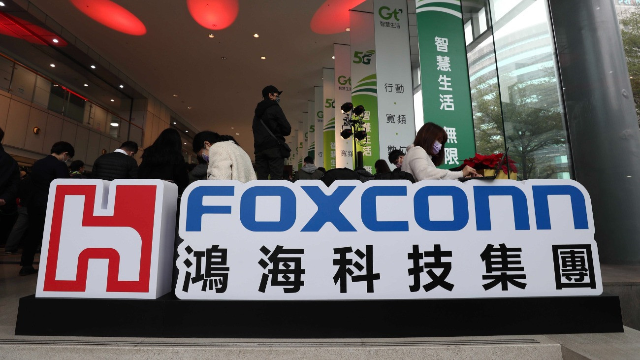 Emberek dolgoznak a Foxconn Technology Group tajvani elektronikai termékeket gyártó cég logója mögött a Foxconn kutatóintézetének megnyitóünnepségén Tajpejben 2021. január 4-én. Sajtóértesülések szerint a Foxconn stratégiai együttmûködésrõl tárgyal az elektromos autók gyártásával foglalkozó, kínai székhelyû Byton startup vállakozással.