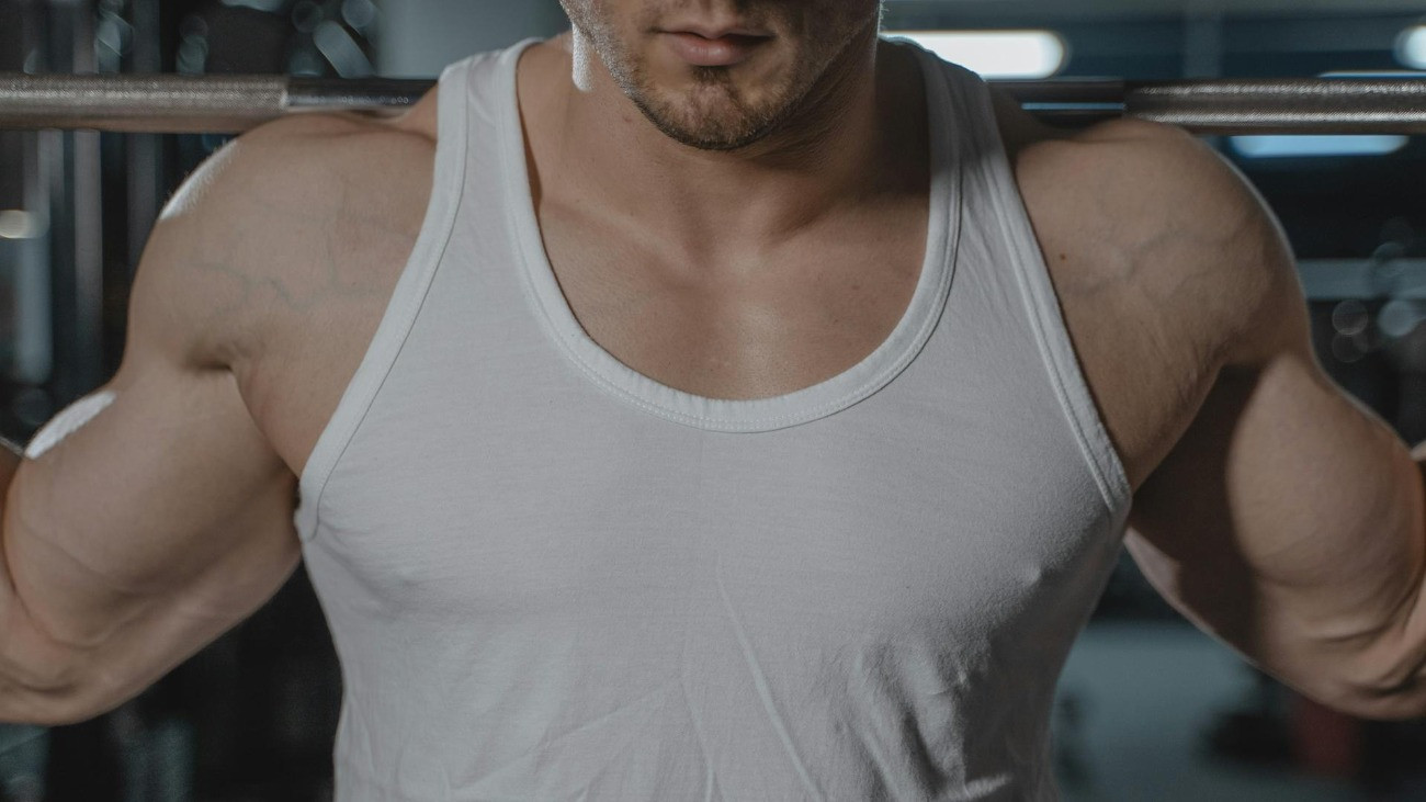 Egy izmos férfi súlyt emel az edzőteremben.