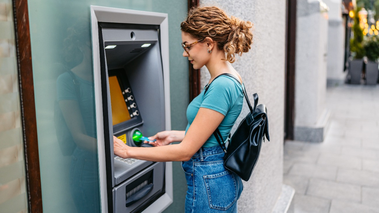 Egy fiatal hölgy pénzt vesz fel egy ATM-automatából Budapesten.