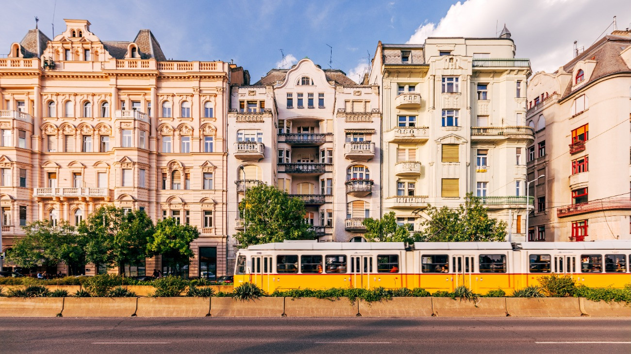 Egy villamos halad el a történelmi épületek előtt Budapesten.