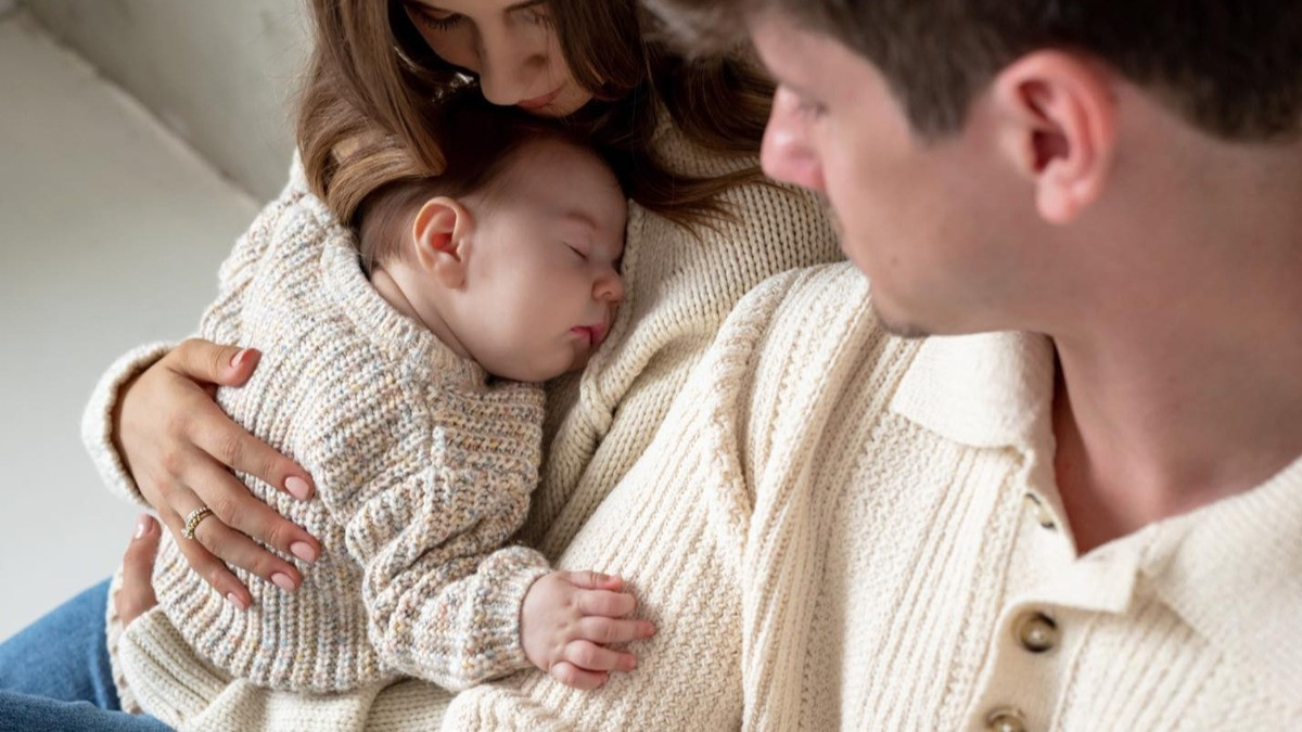 Anya és apa néz egy alaposan felöltöztetett kisbabát