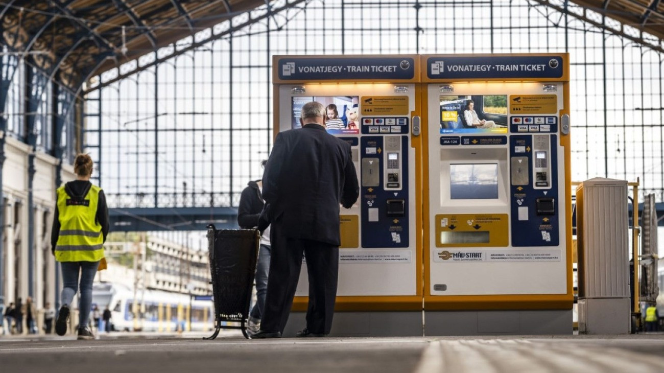 Automata berendezés, ahol az utasok vonatjegyet vásárolhatnak. Egy férfi éppen jegyet vásárol, mert utazni szeretne a Magyar Államvasutak egyik járatán.