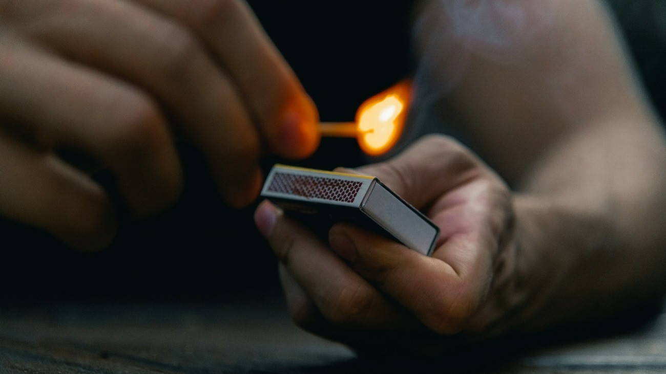 Egy férfi meggyújt egy szál gyufát.