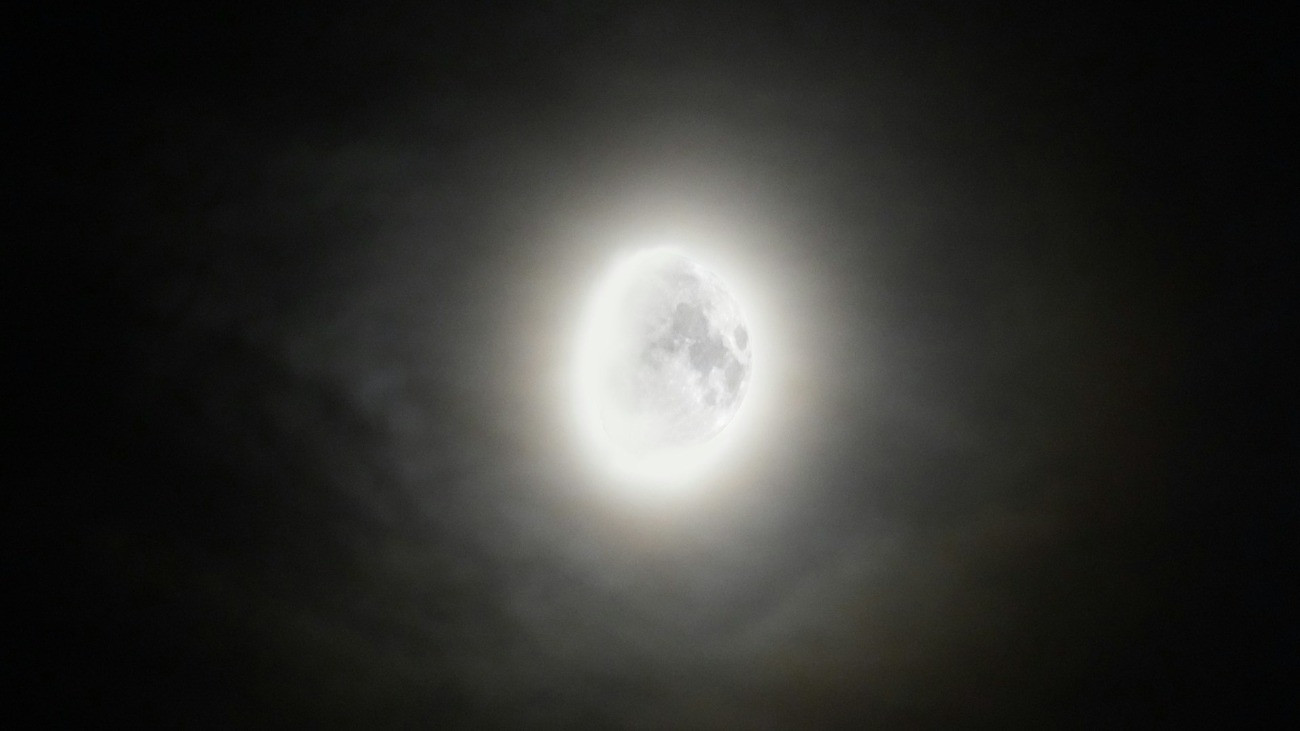 A fényesen ragyogó, növekvő Hold az enyhén felhős éjszakai égen.