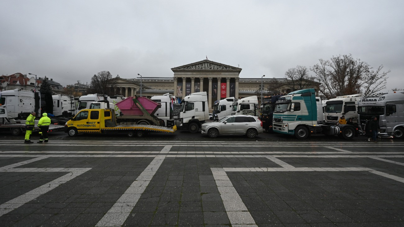 Tüntetõ kamionosok gépjármûvei sorokoznak a fõvárosi Hõsök terén 2025. december 22-én. A fuvarozók a díjak megemelése ellen tiltakoznak. Az Építési és Közlekedési Minisztérium december 19-én hét fuvarozói szervezet képviselõivel írt alá megállapodást; minden fuvarozói szervezettel megegyezett, egy szervezet kivételével. A minisztérium tájékoztatása szerint a megállapodás aláírásával a fuvardíjak méltányos emelése valósul meg 2026-ban.