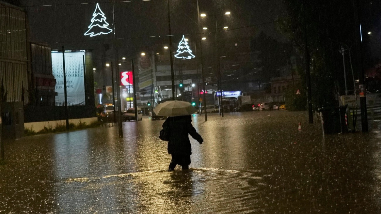 Bokáig érõ vízben gázol egy járókelõ a zuhogó esõben Athénban 2026. január 21-én, amikor egy meteorológiai hideghullám zivatarokat, havazást és szélviharokat okozott Görögország több térségében.