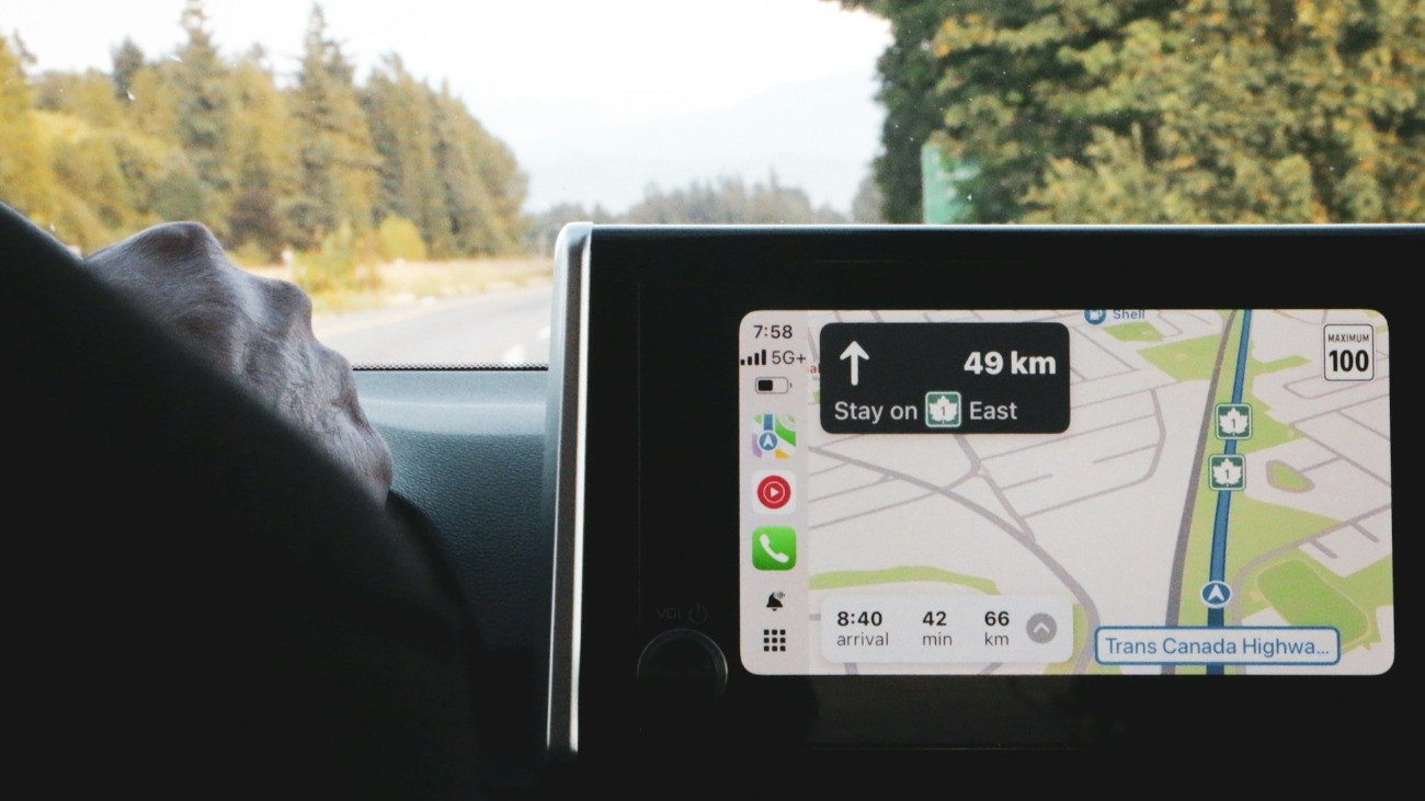 Egy ember autót vezet, miközben az Apple Maps navigációs alkalmazást használja.