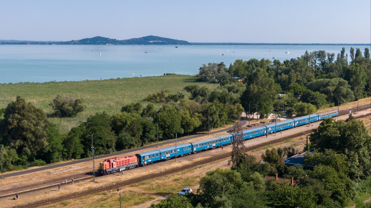 A drónnal készített felvételen retró festésû M40-es Púpos dízelmozdony vontatta személyvonat áll Badacsonytomajon a MÁV balatoni retró hétvégéjén 2025. július 5-én.