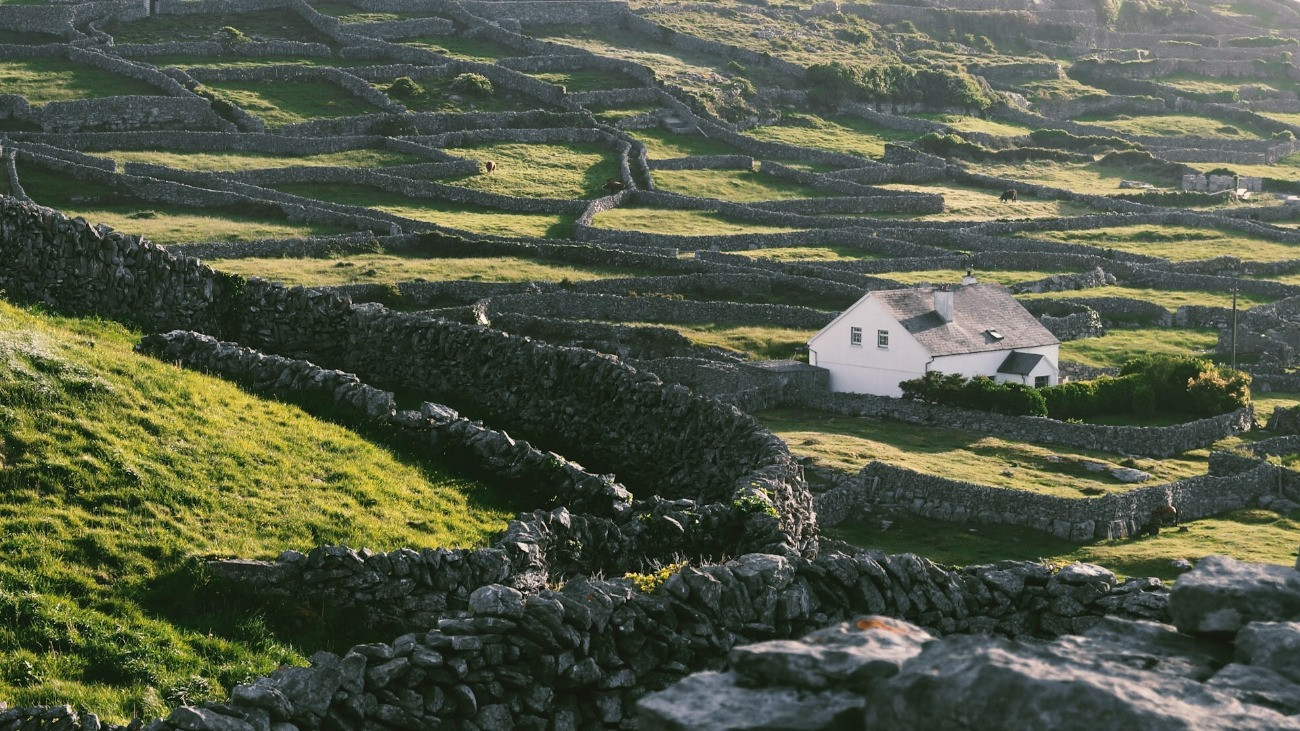 Egy fehér házikó a klasszikus, kőkerítéses felosztású telkek között Galway megyében, Írországban.