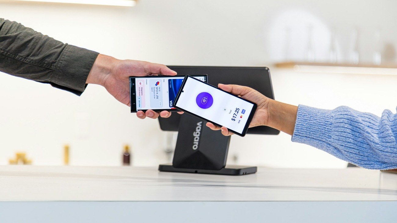 Egy ember a telefonja segítségével fizet egy másiknak digitális tranzakciós rendszerrel.