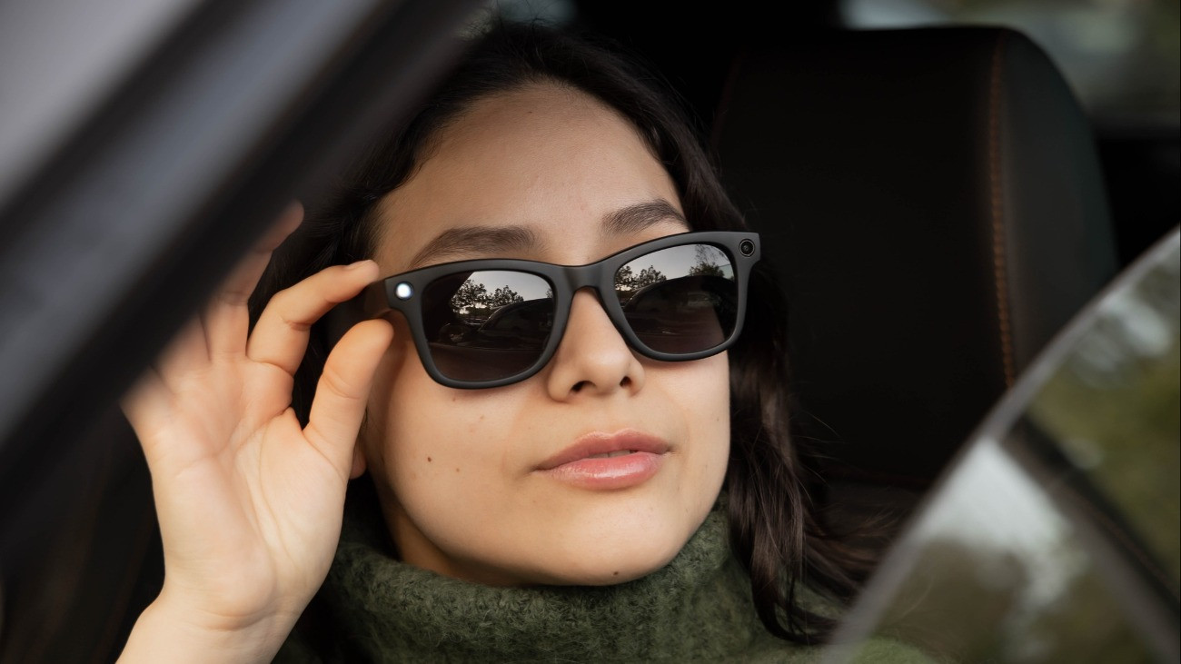 Woman driving a modern car while wearing smart AI sunglasses, showcasing connected technology.