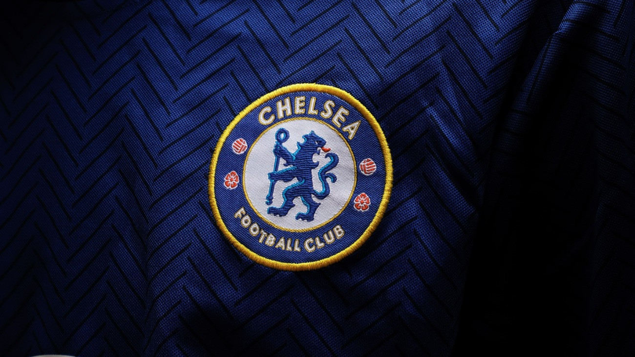Chelsea FC címere egy ágaskodó kék oroszlánt ábrázol, a kezében egy bottal. A címer szélén fehér és arany színű felirat mutatja a csapat nevét, a mintát pedig kis labdák és piros rózsák egészítik ki.