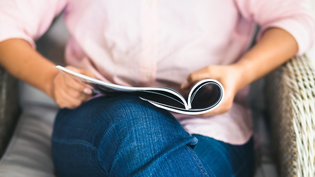 Closeup woman sit in armchair and read the magazine on her lap